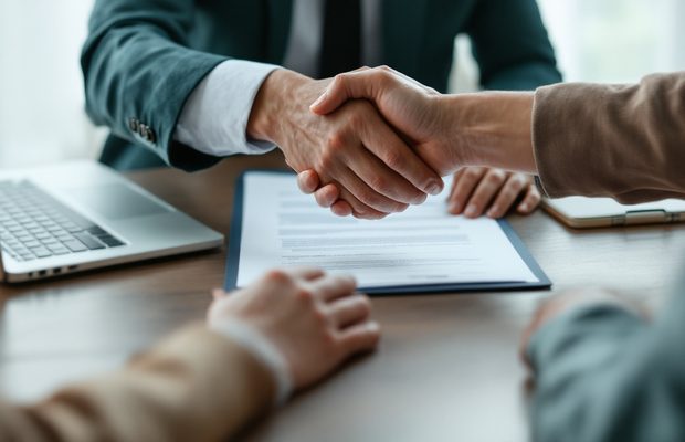 Deux personnes se serrent la main au-dessus d'un contrat signé